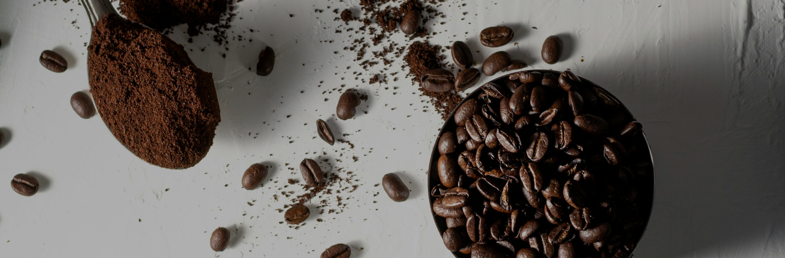Coffee beans and ground coffee on a white surface